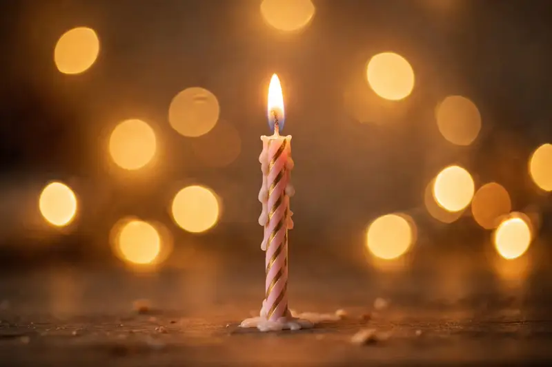 A lit birthday candle glowing in soft golden light, blessings on your birthday