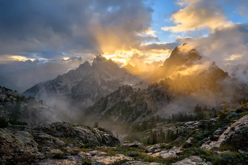 Mountain peaks at sunrise after a storm with clearing clouds and golden light